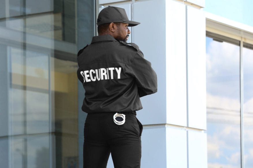 Male,Security,Guard,Standing,Near,Big,Modern,Building - 92.5 The Beat
