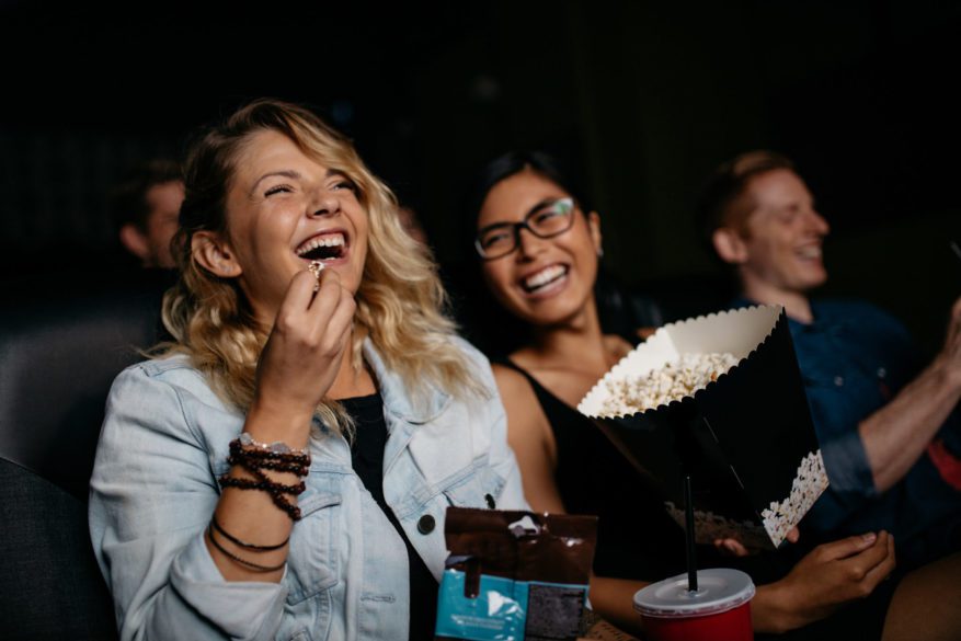 Young,Woman,With,Friends,Watching,Movie,In,Cinema,And,Laughing. - 92.5 The Beat